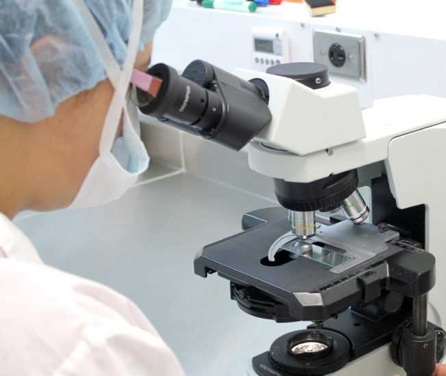 Kvinna tittar i ett mikroskop