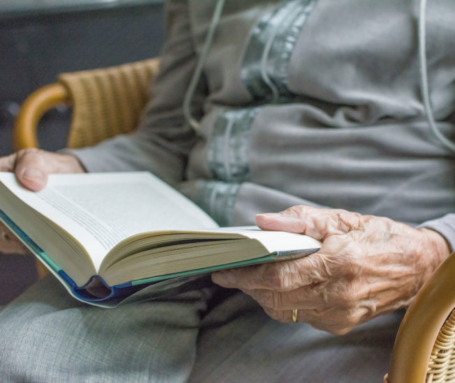 Äldre person som läser en bok.