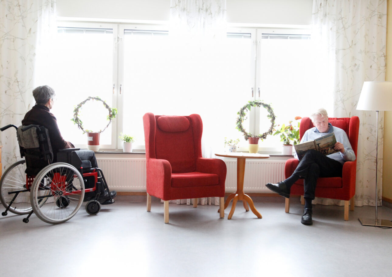 sällskapsdel på äldreboende. kvinna i rullstol och man i fåtölj