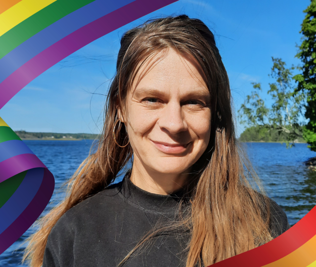 Anna Siverskog framför en sjö inramad av en illustrerad prideflagga