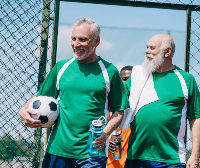 Två äldre män med en fotboll under armen.