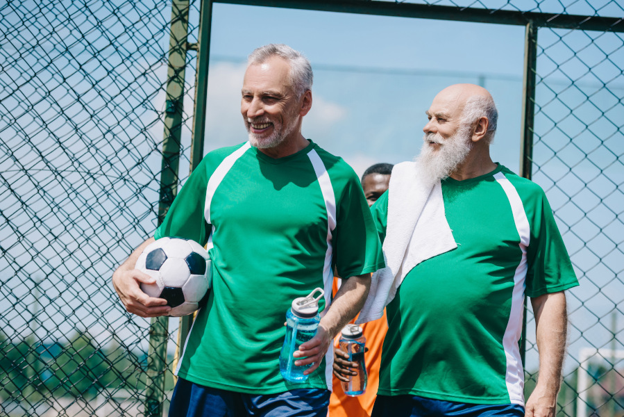 Två äldre män med en fotboll under armen.