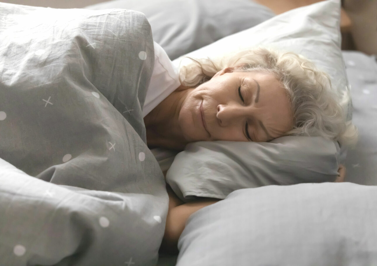 Äldre kvinna som sover i säng