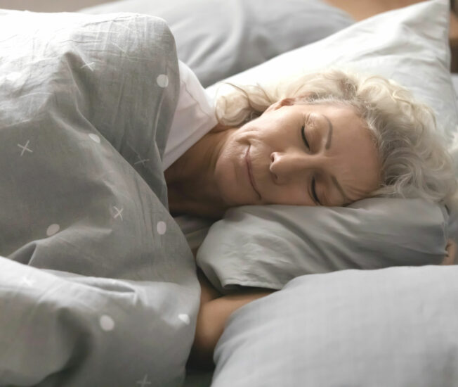 Äldre kvinna som sover i säng