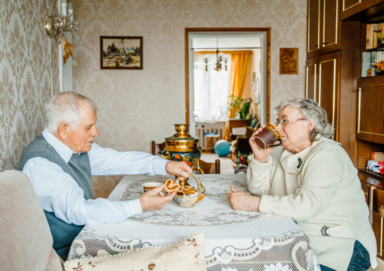 Två personer sitter och fikar i ett ombonat hem.