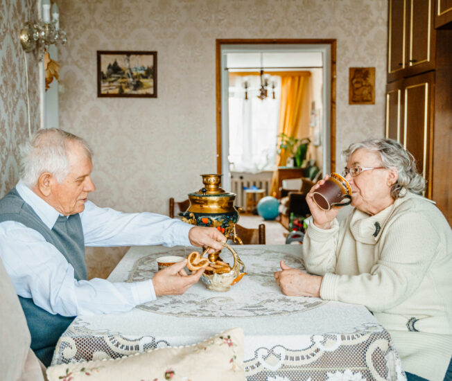 Två personer sitter och fikar i ett ombonat hem.