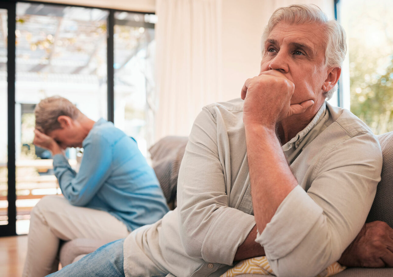 Äldre par sitter i soffa där kvinnan är ledsen, men inte mannen