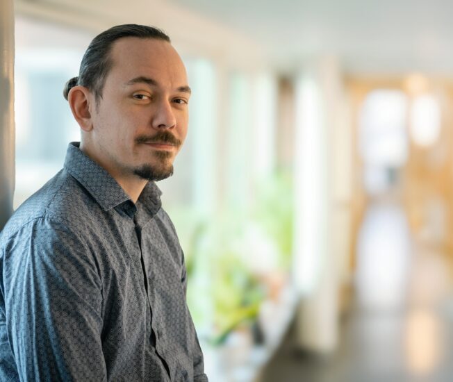 Medelålders man tittar in i kamera från en dörröppning