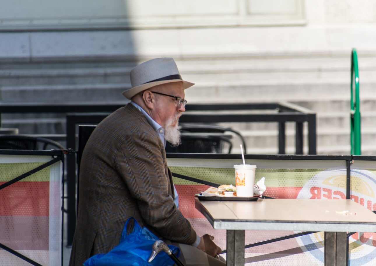 Äldre man äter ensam på en hamburgerrestaurang
