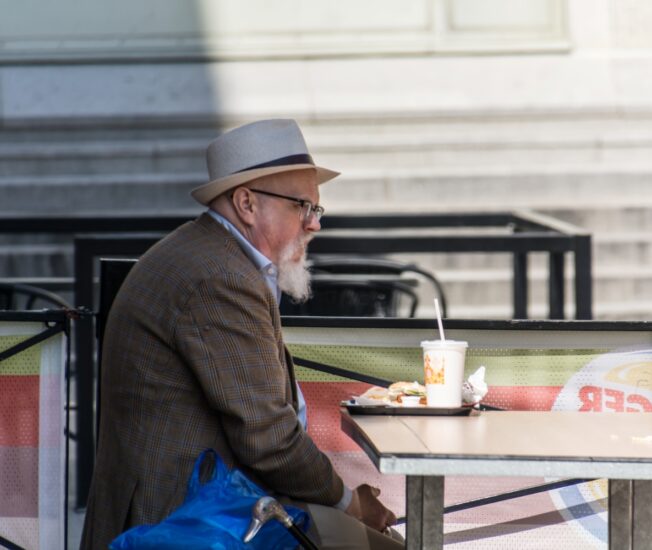 Äldre man äter ensam på en hamburgerrestaurang
