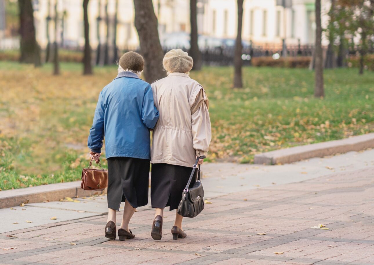 Två äldre kvinnor promenerar hand i hand