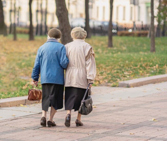 Två äldre kvinnor promenerar hand i hand