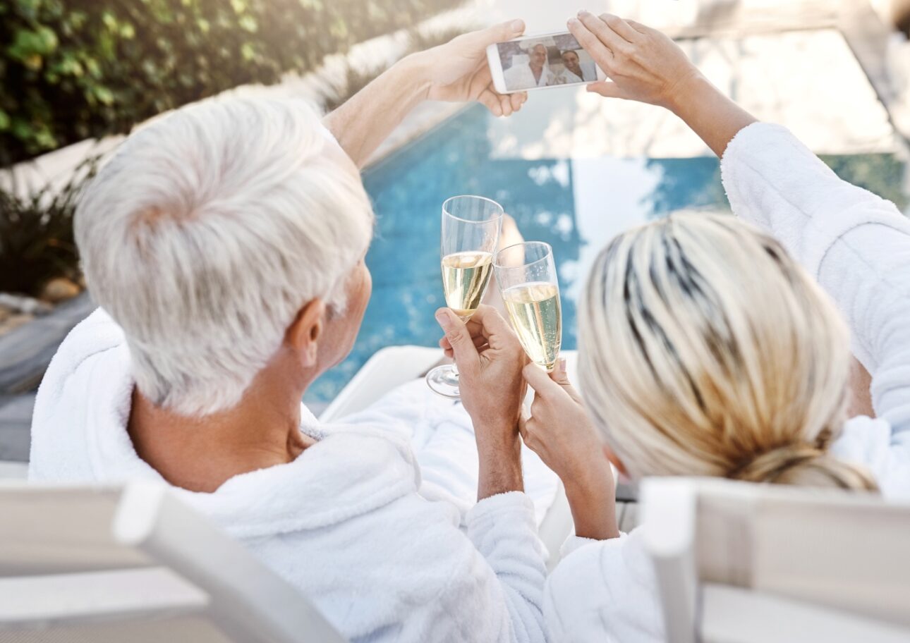 Äldre par dricker champagne vid poolen
