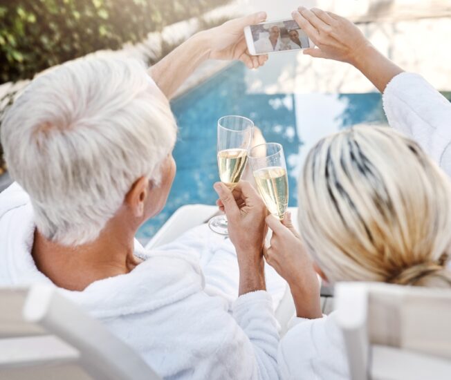 Äldre par dricker champagne vid poolen