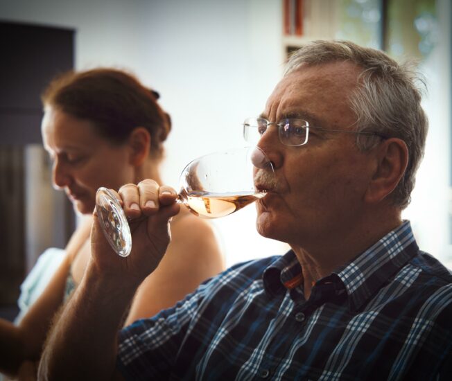 Äldre man dricker ett glas vin