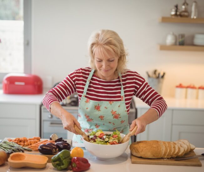 Äldre kvinna mixar sallad