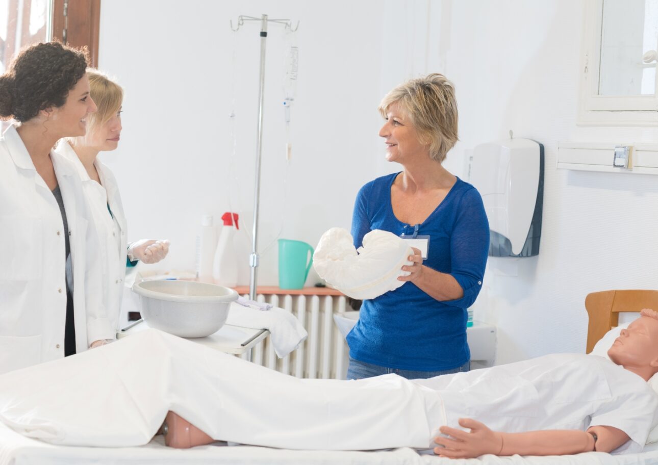 Vårdpersonal lär sig byta blöja på docka