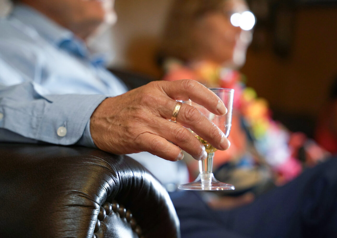 Äldre man håller i ett glas