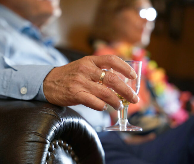 Äldre man håller i ett glas