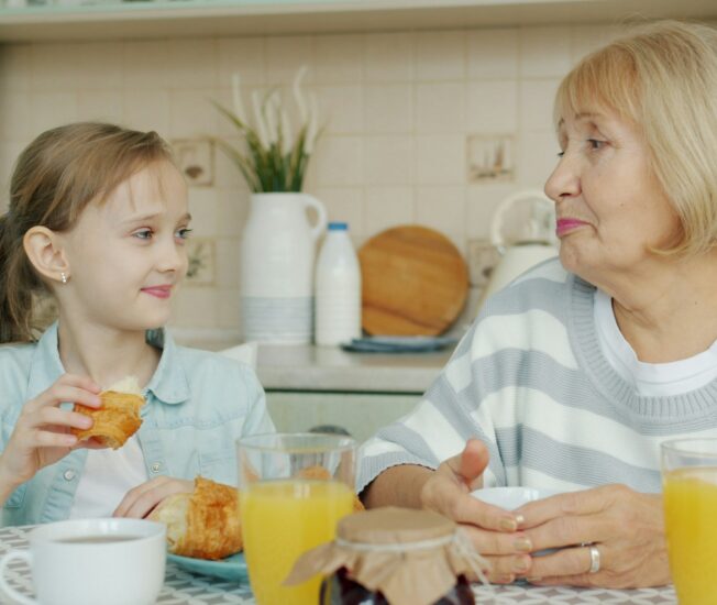 Äldre kvinna sitter vid ett matbord med sitt barnbarn