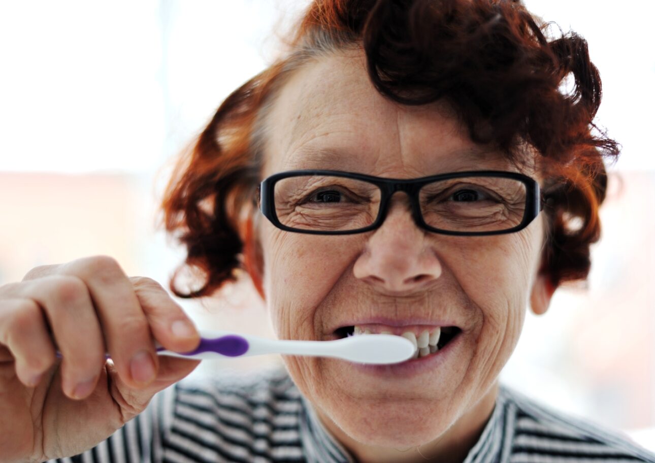 Äldre kvinna borstar tänderna