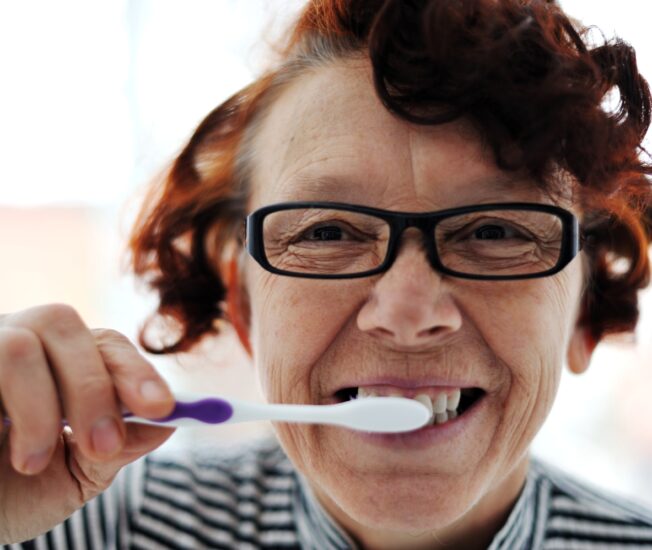 Äldre kvinna borstar tänderna