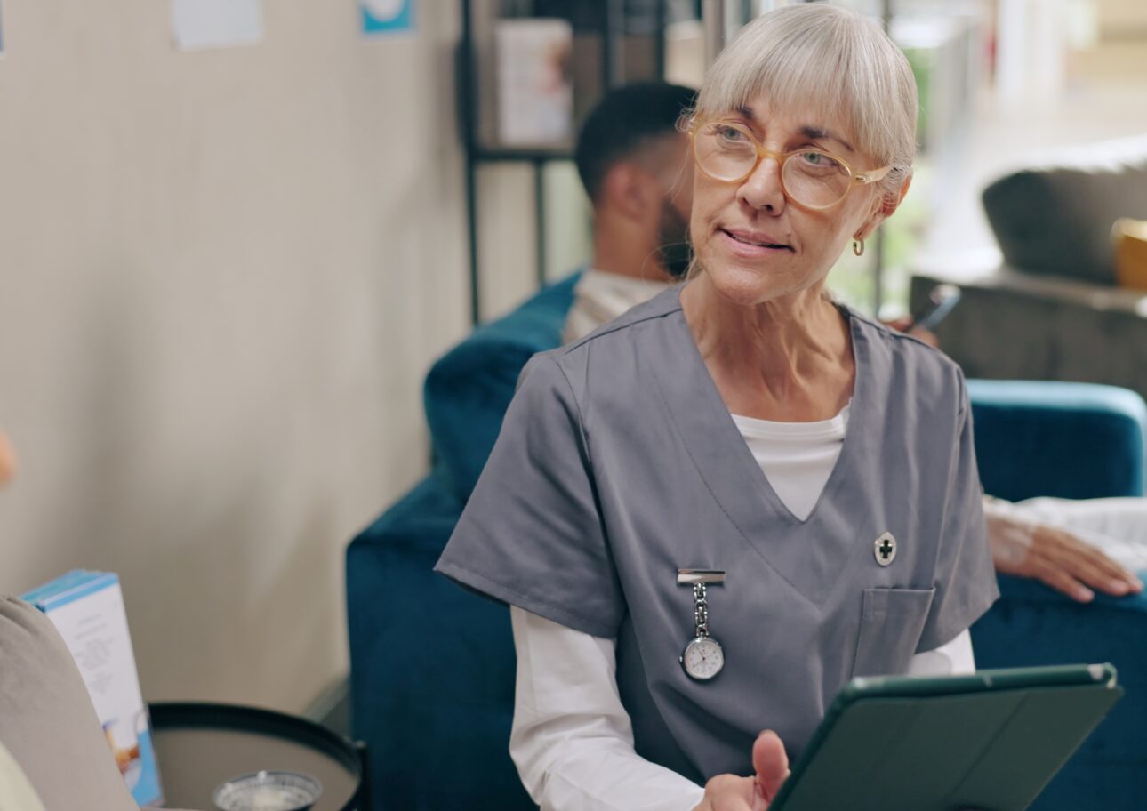Äldre sjuksköterska pratar med patient