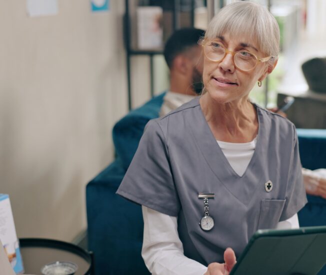 Äldre sjuksköterska pratar med patient
