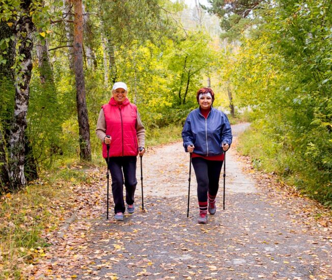Två äldre kvinnor promenerar på en stig