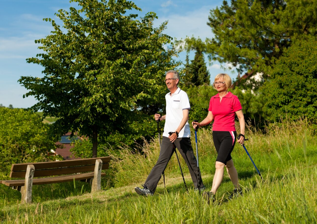 Äldre par promenerar med gångstavar