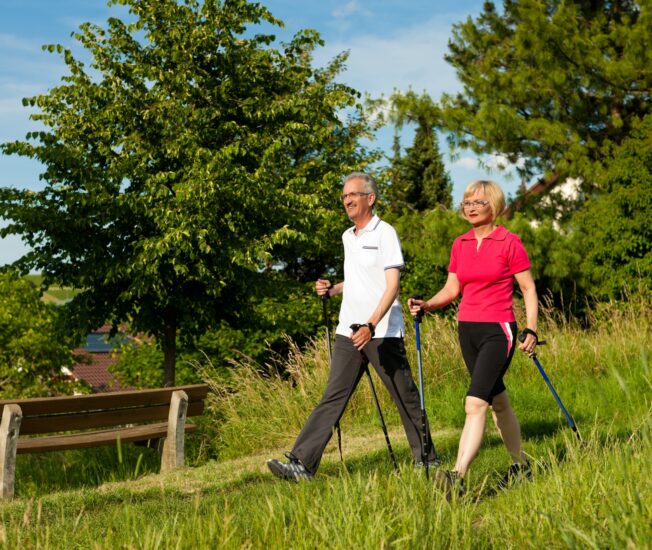 Äldre par promenerar med gångstavar