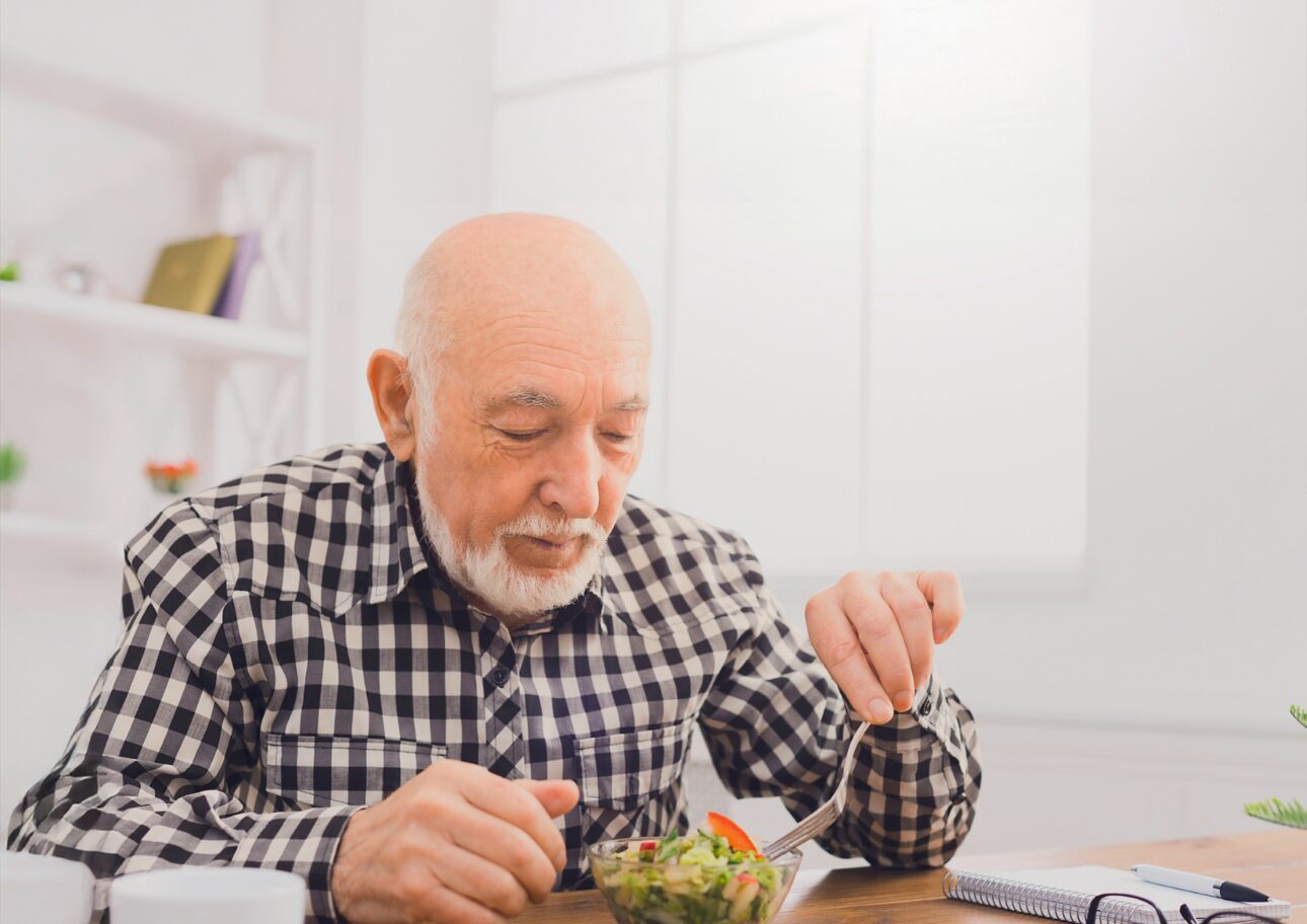 Äldre man sitter och äter