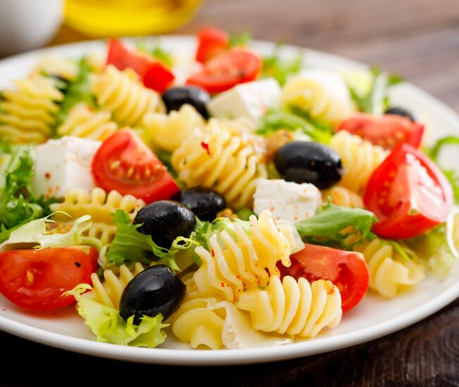 Tallrik med pasta, oliver, tomater och fetaost